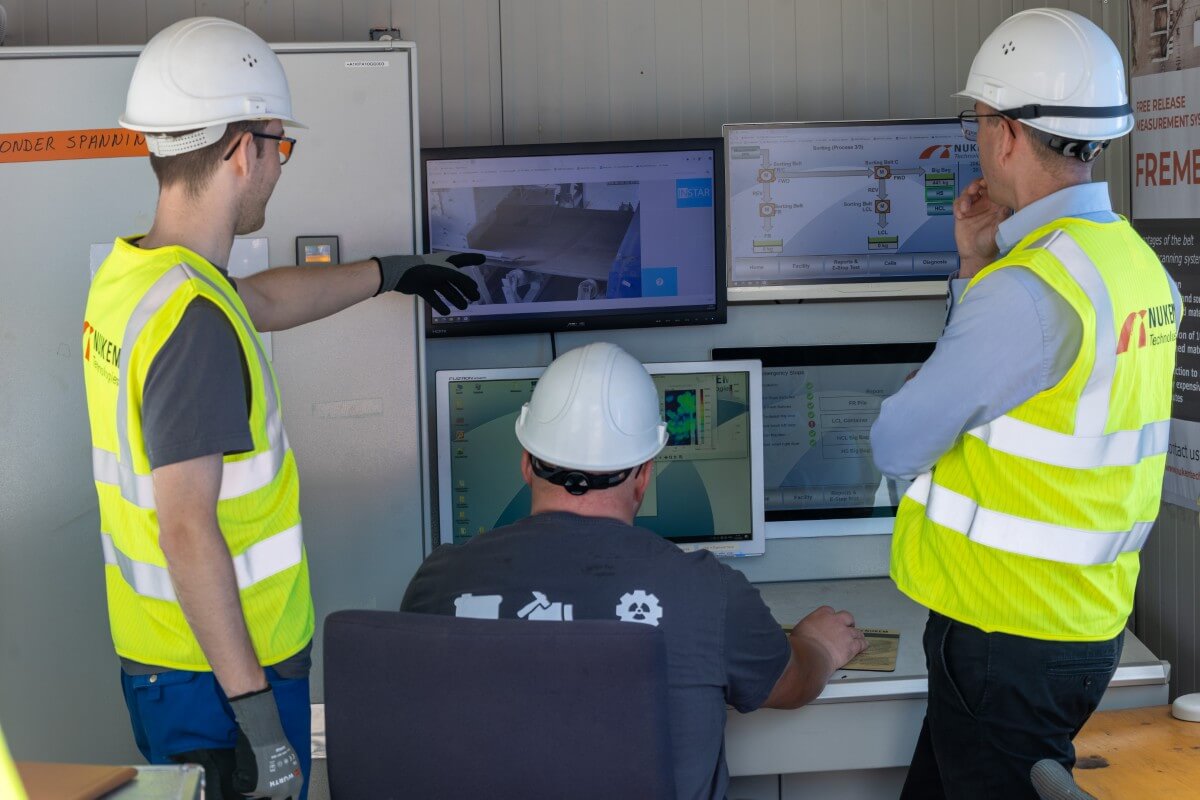 Colleagues consult with each other on a construction site while looking at the screens in front of them.