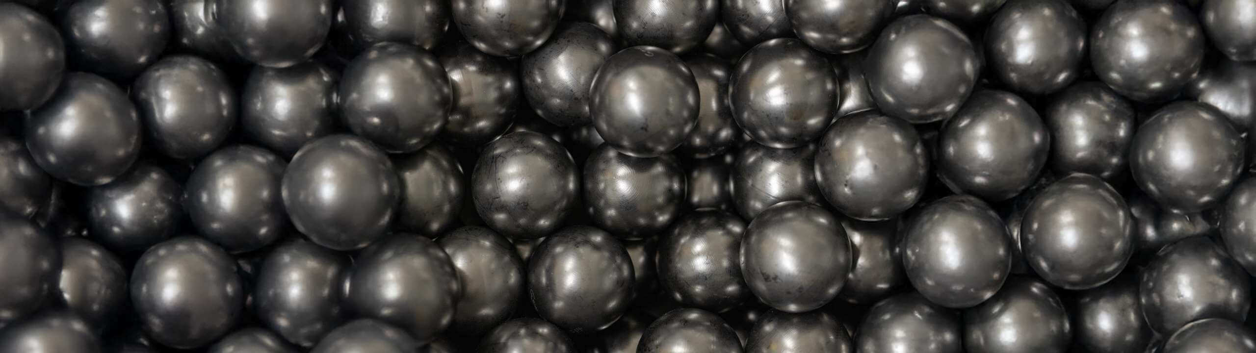 Close-up of many black, shiny balls lined up close together.