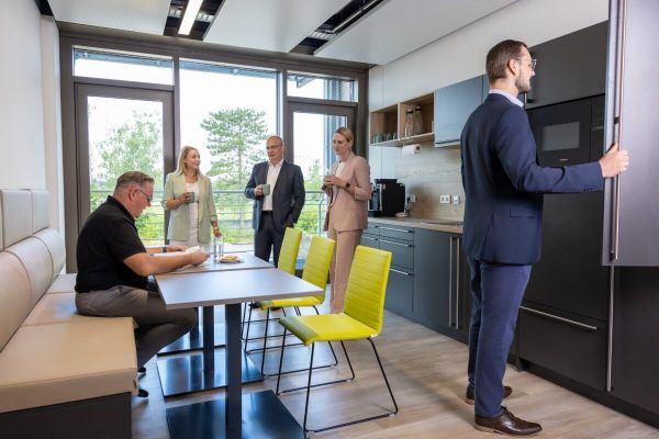 Employees chat together in the staff room, which has a kitchen and tables.